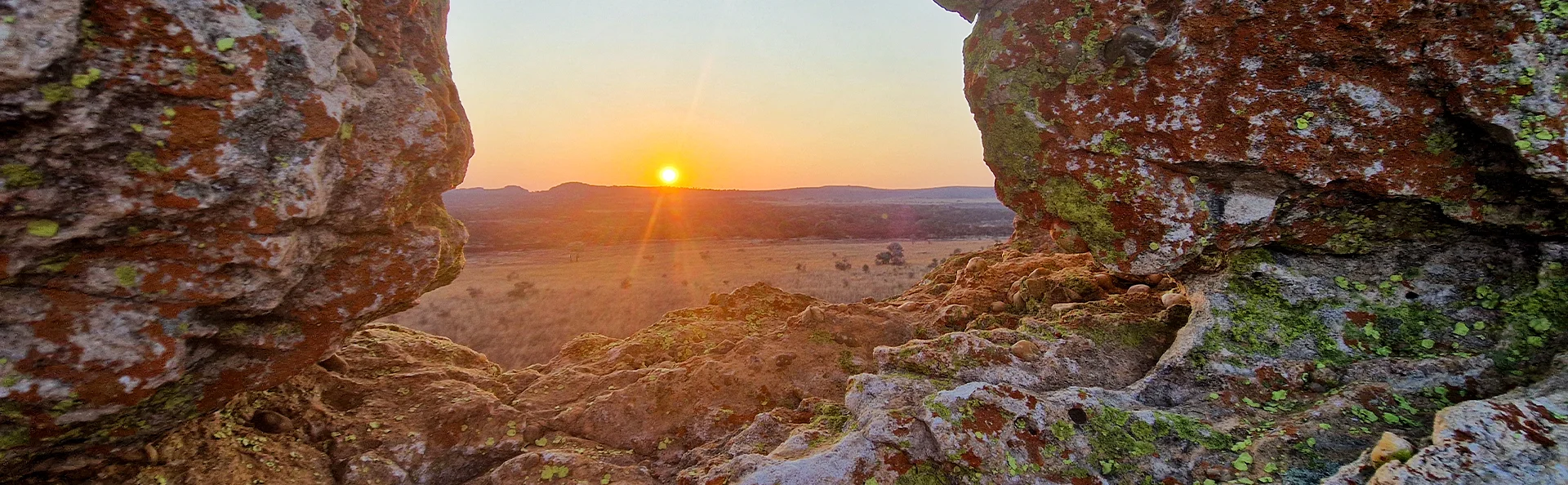 Zonsondergang, omlijst door rotsen, boven het open landschap in het nationaal park Isalo