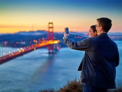 Man en vrouw fotograferen de Golden Gate Bridge bij zonsondergang