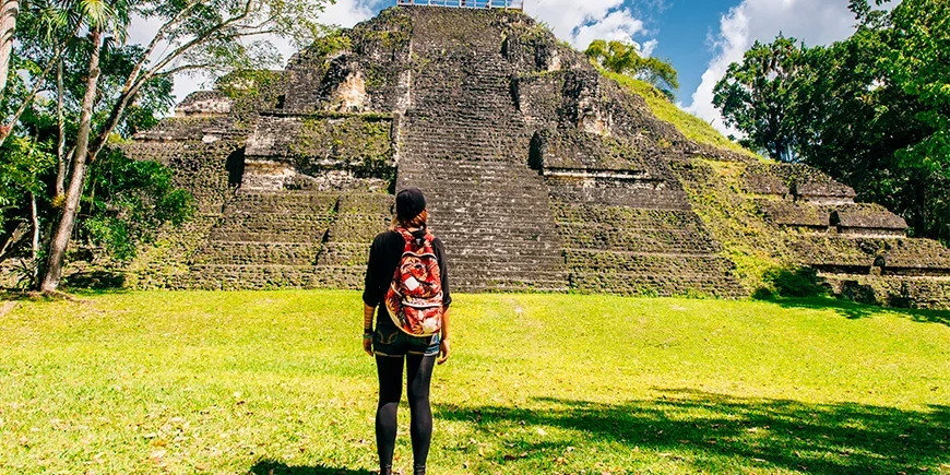 Vrouw die voor een piramide staat in Nationaal park Tikal