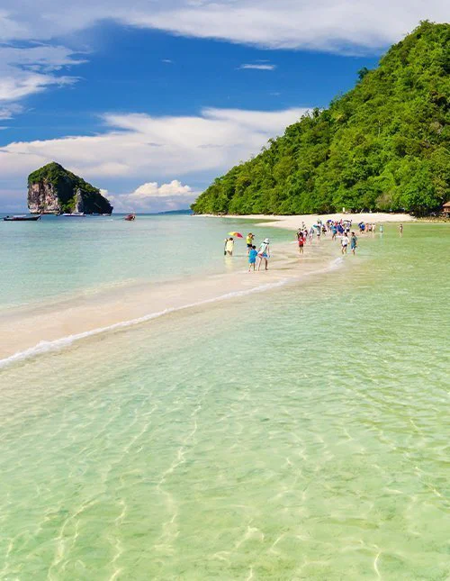 Uitzicht op de zonsondergang over een baai in Thailand, met stadslichten en groene heuvels